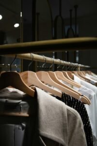 Um guarda-roupa minimalista, com poucas peças de roupas de alta qualidade bem organizadas em cabides, contrastando com uma pilha de roupas descartadas ao lado. A cena deve transmitir durabilidade e simplicidade.